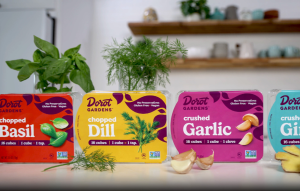 Dorot Gardens: Variety of flash-frozen herb and garlic cubes in colorful packaging. Fresh herbs and garlic nearby.