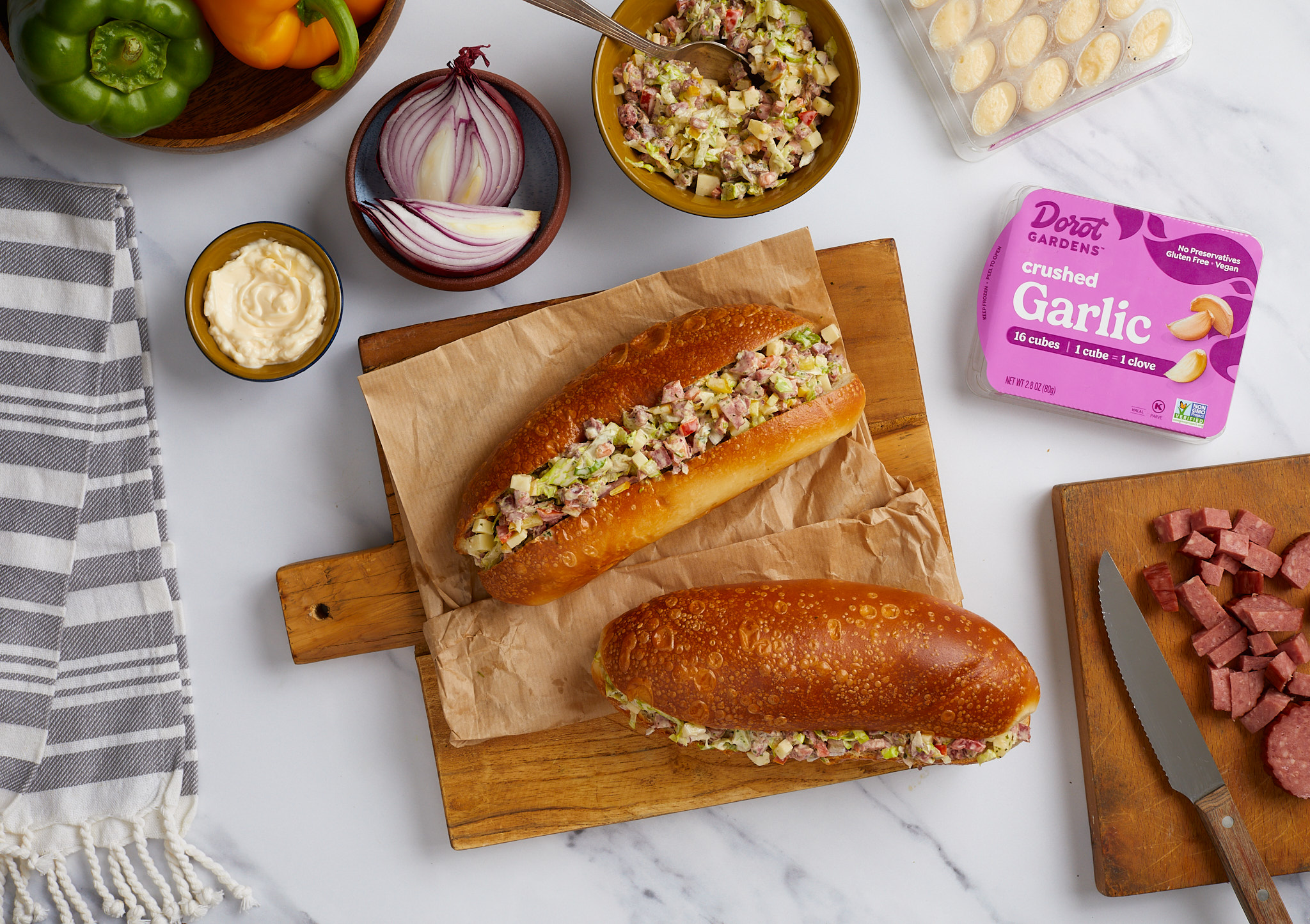 Hot dogs topped with relish beside Dorot Gardens garlic.