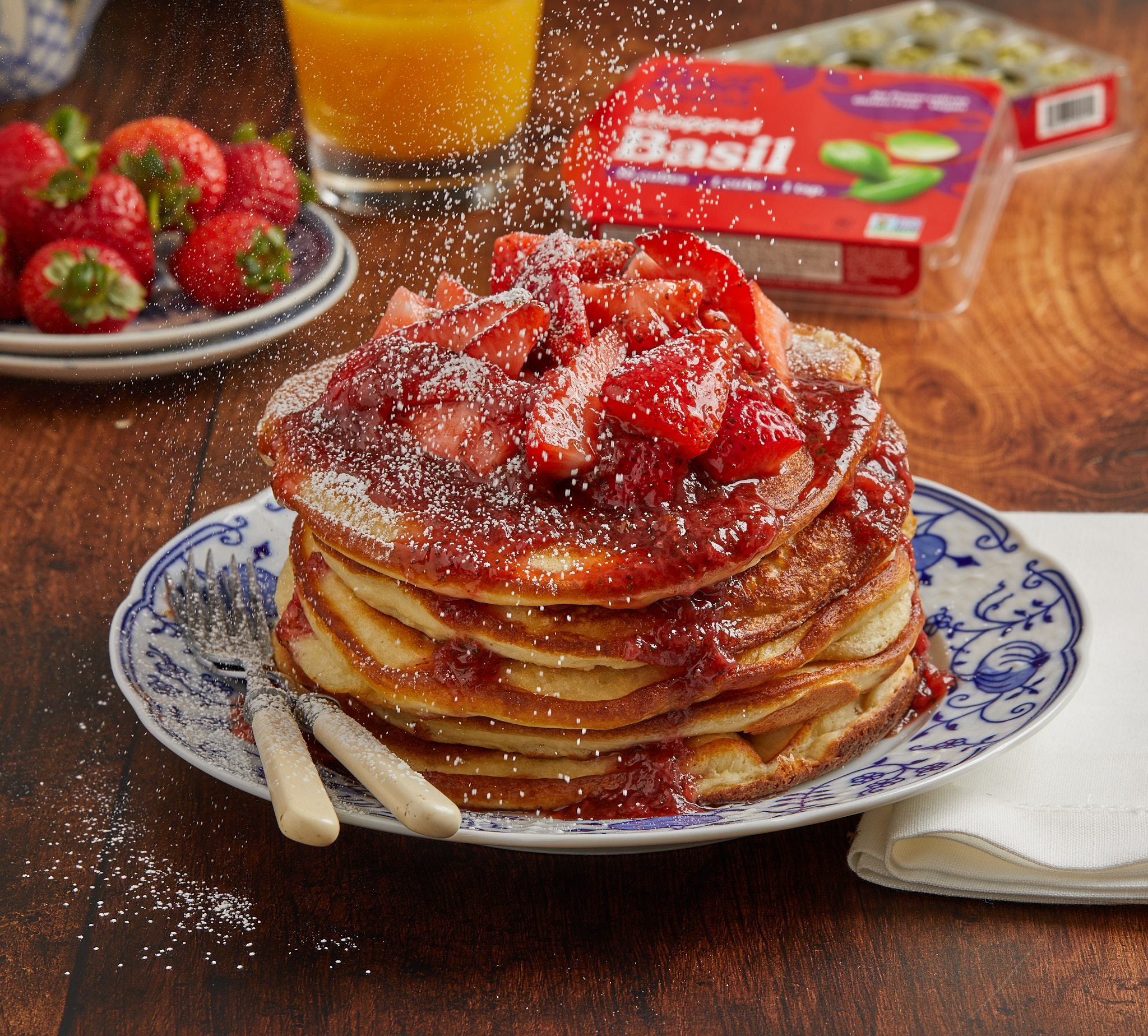 Pancakes topped with strawberries and powdered sugar.