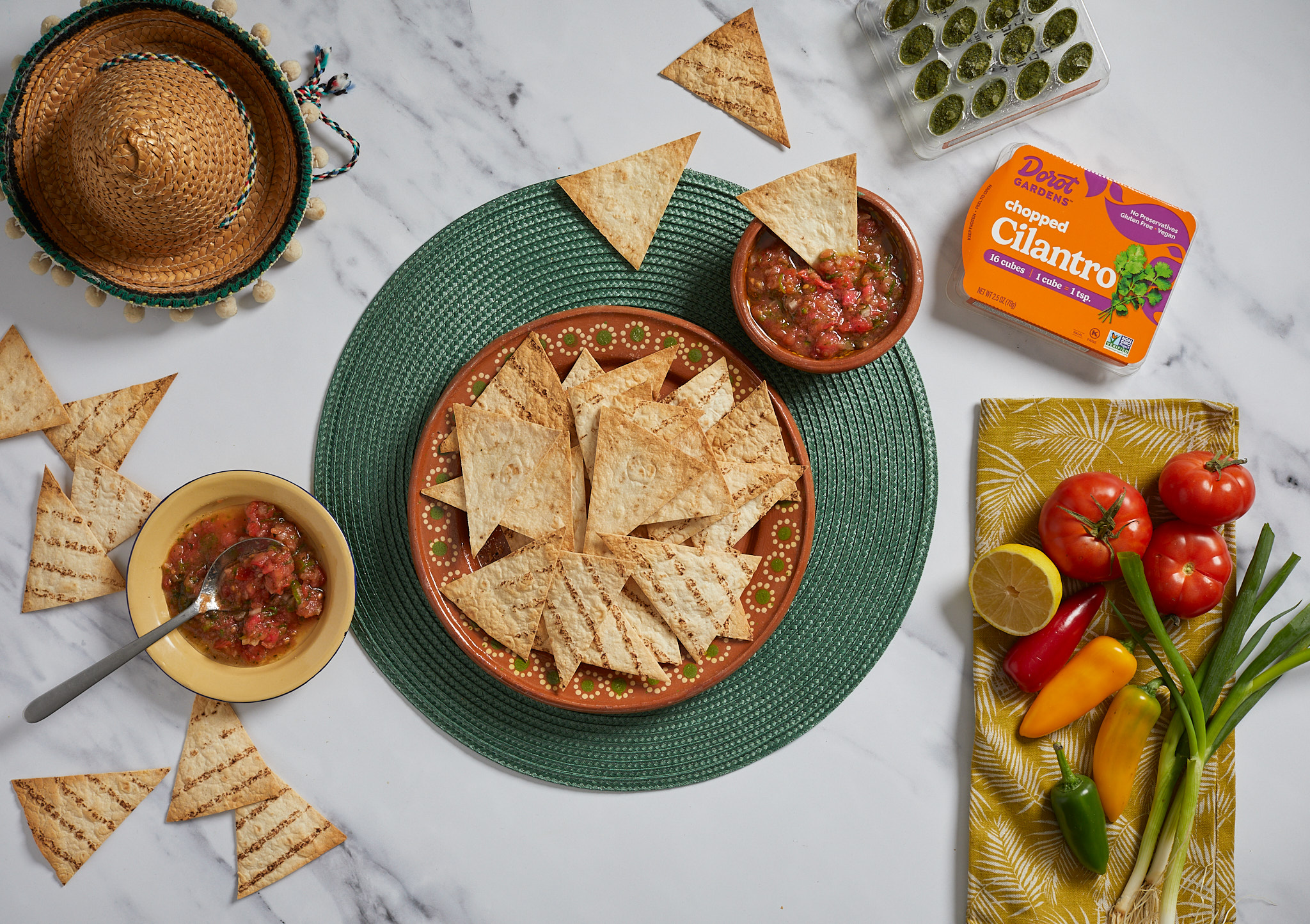 Tortilla chips with salsa, limes, and a Dorot cilantro pack on the counter.