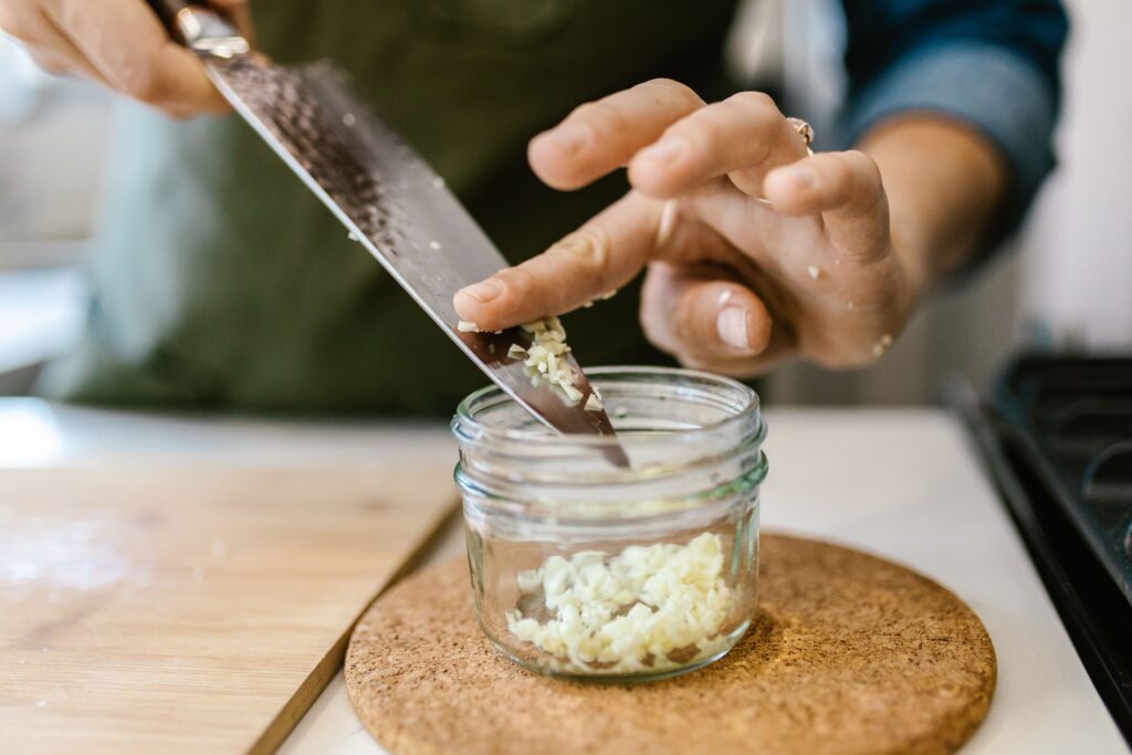Close-up of a woman chopping garlic on a board, capturing the cooking process.